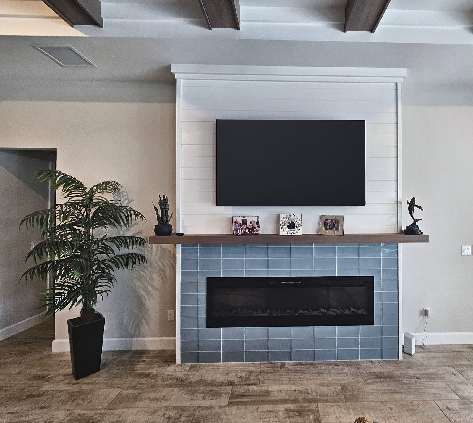 White planked media wall surround with a TV above a wood mantel shelf and a blue-gray fireplace surround below, in a Venice, FL home